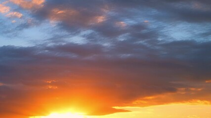 Wall Mural - A sunrise time lapse shows the horizon lit with fiery orange and yellow hues beneath dark clouds, gradually blending into soft blues, reflecting the shifting patterns and moods of morning weather.
