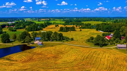 Wall Mural - Bright golden farmland fields under vivid blue sky at sunset with cloud shadows crossing idyllic rural ponds