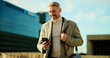 © peopleimages.com - Phone, smile and business man in city for travel, check schedule or update with urban planner. Outdoor, mobile or mature employee on commute, communication and reading text for development approval