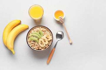 Wall Mural - Tasty oatmeal with fruit, bowl with honey and glass of juice on light background