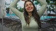 © Krakenimages.com - Young hispanic woman smiles while making heart gesture with hands over head at resort pool; summer vacation love.