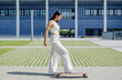 © Westend61 - Businesswoman skateboarding in front of modern office building outdoors