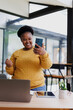 © MINAE - Cheerful african american businesswoman is making a video call on her phone, expressing her excitement and celebrating a positive outcome in her bright modern office
