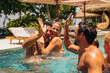 © Jacob Lund - Joyful group of friends sharing a high-five in pool on sunny holiday getaway