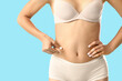 © Pixel-Shot - Young woman in underwear with cellulite problem on blue background, closeup
