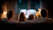 © pima - Parents and two children enjoying movie night on sofa, back view, illuminated by warm indoor lighting, depicting family bonding and home leisure time