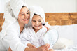 © Prostock-studio - Cheerful little girl looking at mirror, putting blush on her cheeks and smiling. Beautiful mother and daughter in bathrobes having beauty day at home, applying make up on their faces, copy space