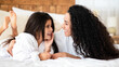 © Prostock-studio - Beautiful young mother and little daughter in bathrobes laying on bed at home, hugging and laughing, copy space. Happy mom and kid spending time together in cozy bedroom, closeup portrait