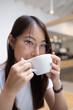 © Wuttichai Kaewklang - A woman wearing glasses is drinking from a white cup. Chilling work place