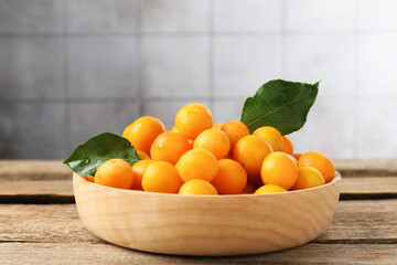 Wall Mural - Ripe yellow cherry plums and leaves on wooden table, closeup