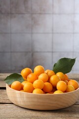 Wall Mural - Ripe yellow cherry plums and leaves on wooden table. Space for text