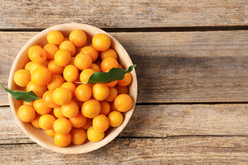 Wall Mural - Ripe yellow cherry plums and leaves on wooden table, top view. Space for text