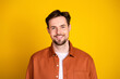 © deagreez - Young man wearing a casual orange shirt smiles confidently on a vibrant yellow background, exuding charm and positivity