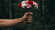 © muaz - An adult male hand firmly grasping mixed-color Carnations, against a dark, moody forest background. Suggesting strength and cheer