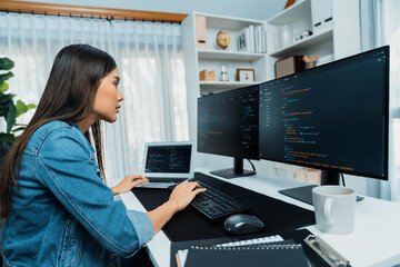 Young Asian in IT developer creating with typing online information on pc with coding program data of website application, wearing jeans shirt. surrounded by safety analysis two screens. Stratagem.