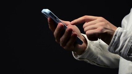 Man in white shirt with smartphone in hands on black isolated background.
Business and conference.
Online communication with partners.
Typing text on smartphone