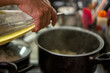 © Guillermo Spelucin - Chef pouring olive oil into pot with meat sauce for ravioli