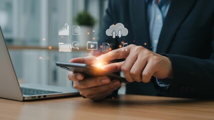 Person using smartphone with digital icons overlayed next to laptop on a wooden desk surface view