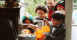 © FantiFlash/peopleimages.com - Children, woman and sweets at door on halloween for tradition, support and trick or treat. Holiday, neighborhood kids and happy with bucket at house for candy collection, fantasy dress up or festival