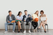 © Pixel-Shot - Group of teachers sitting in chairs near light wall