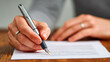© PixelNexusArt - Person holding pen writing on paper with regulatory and science documents in focus for professional work