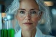 © Olya - Close-up of a confident mature woman with gray hair and glasses looking directly at the camera in a laboratory setting with green liquid in test tubes