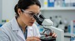 © Telrkmark - A female scientist meticulously examines a sample through a microscope in a laboratory setting, focused on research.