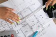 © fotodrobik - Hands Measuring Construction Blueprint with Various Tools and Equipment Effectively