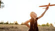 © Mariia - Child aviator with airplane dreams of traveling in summer in nature at sunset. Girl with plane on meadow. Summer leisure.