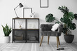 © New Africa - Stylish grey armchair, shelving unit and houseplants indoors. Interior design