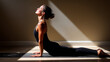 © Createya - Young caucasian female practicing yoga in sunlit room with dramatic shadows - concept of fitness and well-being by yoga studios and wellness centers