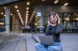 © Apichat - Young asian woman listening to music on laptop with headphones outdoors