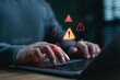 © Looker_Studio - Cybersecurity warning concept with alert icons and coding on laptop screen. Businessman facing system error, malware threat, hacking risk, or data breach during software development or online work.