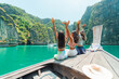 © CandyRetriever  - Happy Asian woman friends sitting on wooden boat travel the sea on summer beach holiday vacation. Attractive girl enjoy outdoor lifestyle looking beautiful nature of tropical island at Krabi, Thailand