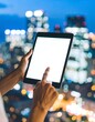 © Kabol - Person using tablet at night with city lights