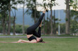 © Wanchai - Asian woman practicing yoga peacefully in the park after work, finding relaxation and balance at sunset.