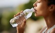 © simba kim - a young woman holding a transparent plastic water bottle and drinking fresh water.