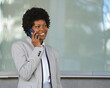 © VictorCanalesStudio - Smiling businesswoman talking on phone outside office building with copy space
