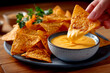 © Ivan Muñoz Colorado - Hand dipping nachos into cheese sauce