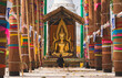 © Ohayo - Asian woman praying in front of golden buddha statue at temple surrounded by colorful fabric decorations, Representing culture and buddhist faith in thailand
