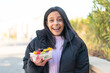 © luismolinero - Young woman at outdoors holding a bowl of fruit at outdoors with surprise and shocked facial expression