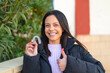 © luismolinero - Young woman holding invisible braces at outdoors with thumbs up because something good has happened
