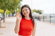 © luismolinero - Young woman with glasses at outdoors saluting with hand with happy expression