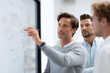 © SolaruS - Team collaborating on ideas. Man explaining strategy on whiteboard, coworkers listening. Illustrates teamwork, planning, innovation. Ideal for business concepts.
