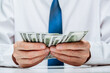© lunika - well-dressed person carefully counts stack cash while sitting at desk in professional office. concept investment, success, financial prospects and career growth. focus is on money in hand. close up.