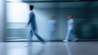 © Nakarin - Blurred silhouettes of medical staff walking in hospital corridor showing dynamic movement and busy healthcare environment