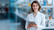 © Anthichada - Portrait of a young female pharmacist in labcoat and holding digital tablet while looking at the camera in a drugs store