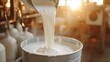 © Suphawan - Pouring creamy goat milk into bucket, with focus on flow and texture, ideal for concepts of farm life and fresh dairy