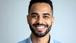 © Suaib - A cheerful man with a wide smile and a light blue shirt against a neutral background presents a positive and approachable demeanor.