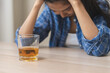 © KMPZZZ - Alcoholism drunk, sad asian young woman hand holding glass of alcohol or whiskey, alone depressed female drink booze on background. Treatment of alcohol addiction, suffer abuse problem alcoholism.
